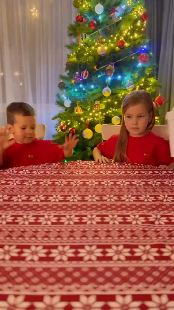 Vaikai su raudonais šventiniais drabužiais kuria namuose.