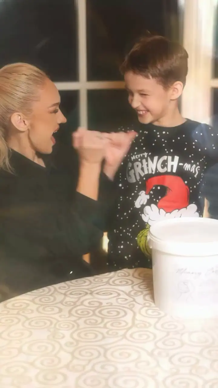 Besijuokiantys mama ir sūnus kuria rankų skulptūrą.